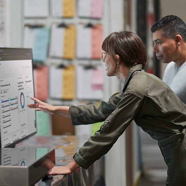 Two people reviewing an analytics report on a desktop computer. Two people reviewing an analytics report on a desktop computer.