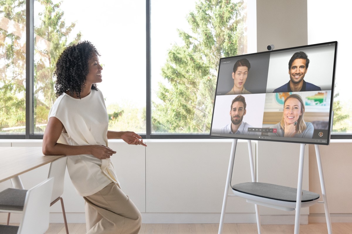 A person in an office along engaging with a Microsoft Teams calls with four faces on video.
