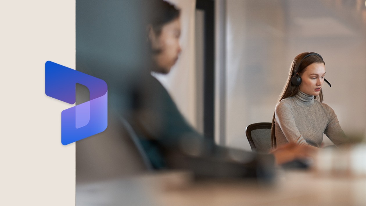 Two coworkers sitting next to each other at a conference room table. There is a thick beige border on the left side of the image, with the Dynamics 365 logo overlaid.