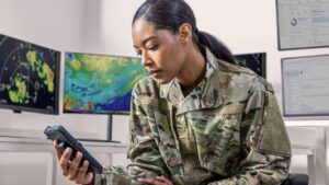 A woman in military uniform looking at a cellphone
