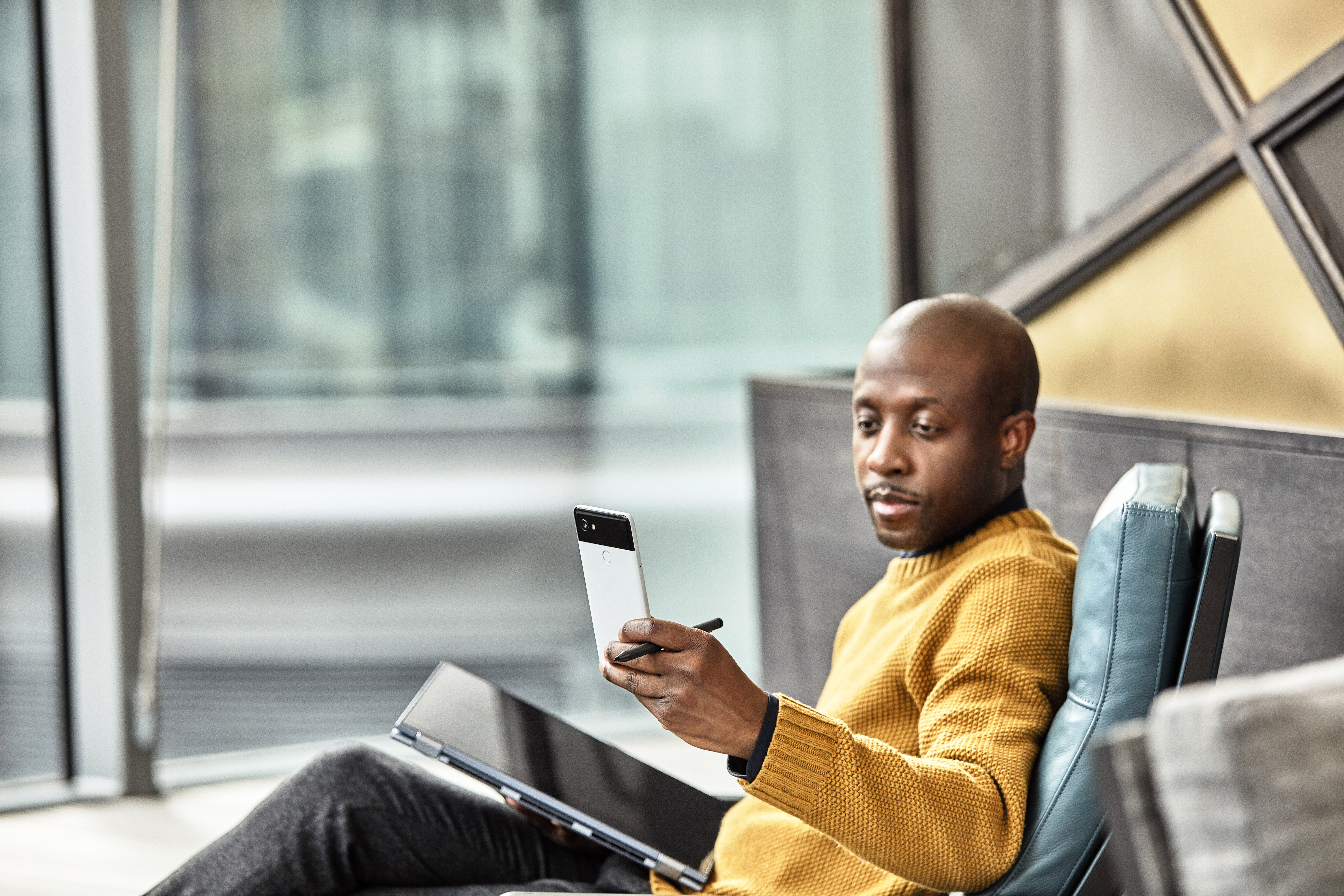 A man is using his Lenovo laptop like a tablet while sitting in a comfortable chair in a Modern office setting