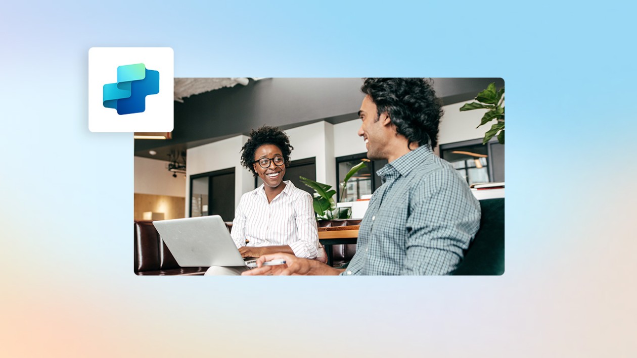 A man and woman sitting at a table with a laptop.