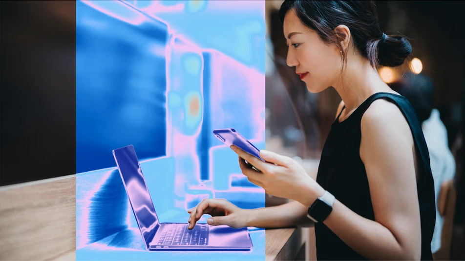 A woman using a laptop and a phone