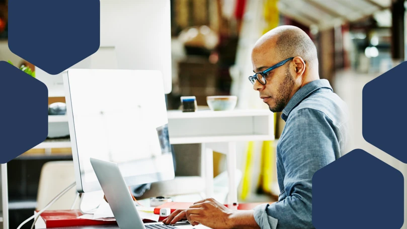 Photo of businessman sitting at workstation in startup office working on project on laptop